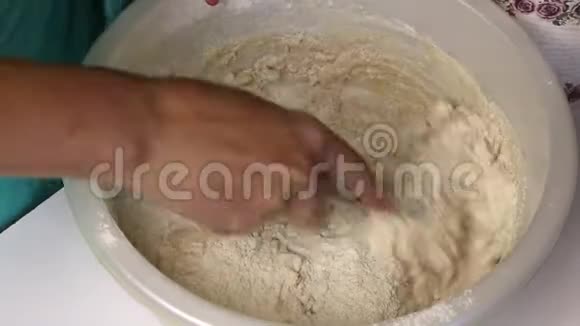 整粒面粉筛入盆中倒入矿泉水女人用勺子揉面团视频的预览图