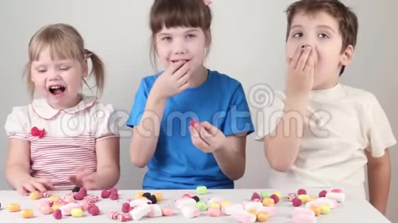 三个孩子吃糖果坐在桌旁视频的预览图