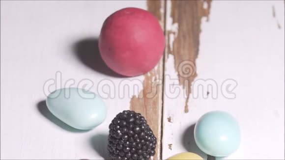 白色谷仓木材表面上的彩色甜糖果淘洗视频的预览图