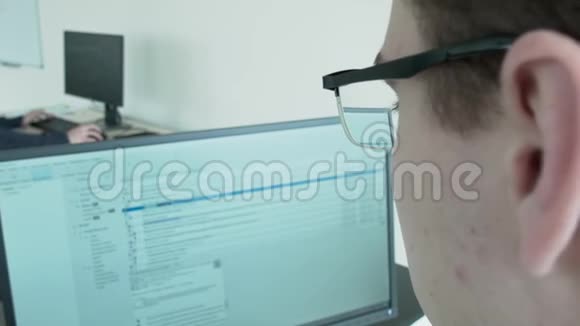 一个年轻的程序员正在窃听这个程序照相机通过眼镜向监视器放大视频的预览图