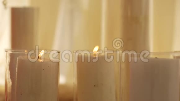 在庆祝厅的地板上玻璃瓶中燃烧着蜡烛上面覆盖着白色的织物和米色的窗帘视频的预览图