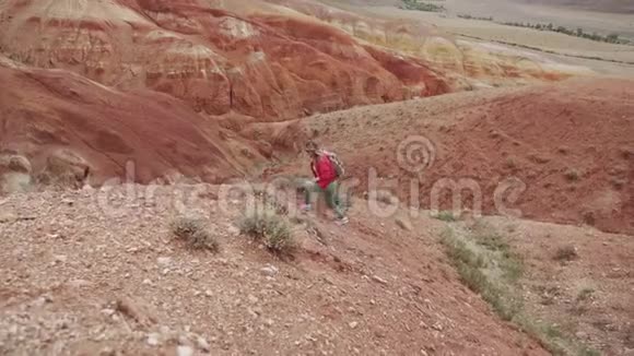 旅行者登上一座陡峭的小山一个背着背包戴着墨镜的旅游女孩走在山区视频的预览图