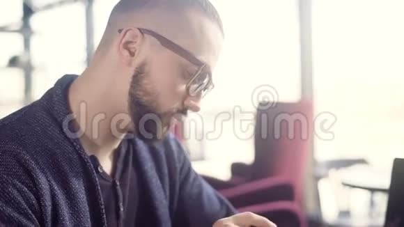 男人检查时间戴眼镜的年轻人坐在咖啡馆的桌子上检查时间视频的预览图