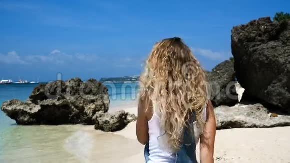 年轻的金发女孩带着岩石和微笑沿着白色海滩奔跑我觉得很自由视频的预览图