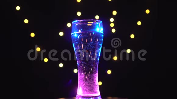 一杯淡蓝色的水在旋转粉色蓝色鸡尾酒酒吧概念视频的预览图