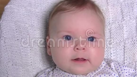 可爱的蓝眼睛宝宝躺在毯子上笑视频的预览图