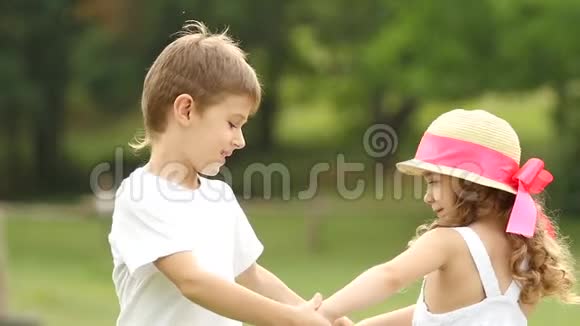 孩子们牵着手开始一起在夏天的公园里转圈慢动作视频的预览图