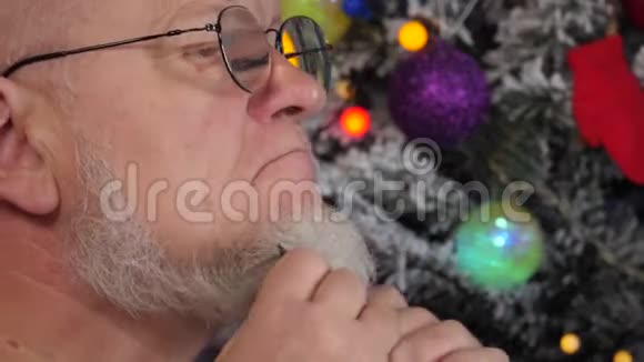 快乐的老人在花环上的圣诞树背景上用梳子梳理他的灰色胡须绿色的UFO球质子紫色玩具视频的预览图