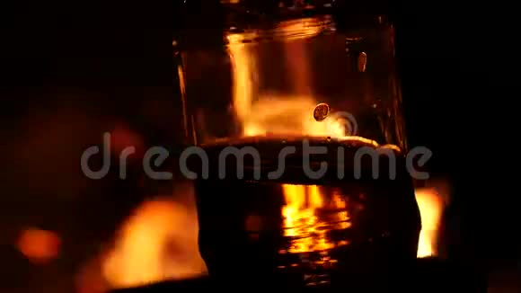 啤酒瓶在黑暗中的火背景上棕色玻璃上的火焰游戏4K视频的预览图