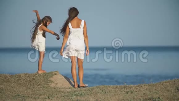 妈妈带着女儿穿着白色裙子靠近大海视频的预览图