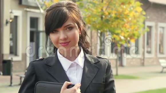 美丽微笑的商务女性背景上的现代办公拿着平板电脑视频的预览图