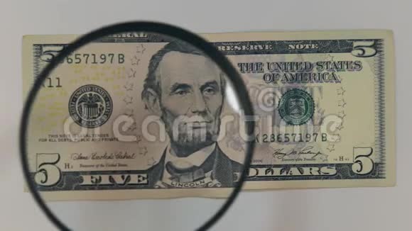 用放大镜接近5美元钞票视频的预览图