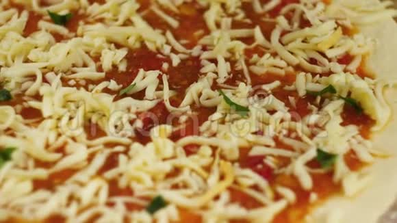 做披萨厨师把奶酪和罗勒放在比萨饼的底部涂上番茄酱男女订婚视频的预览图