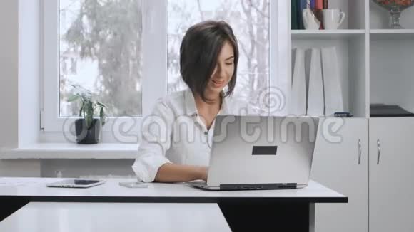 穿白衬衫的漂亮女孩在办公室的电脑里工作视频的预览图
