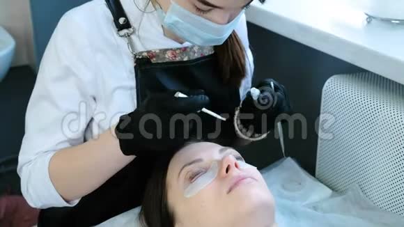 美容治疗美容师把卷发器贴在女人的眼皮上视频的预览图