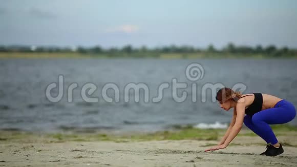 美丽的运动女孩在流动的河流附近的海滩上跳跃视频的预览图