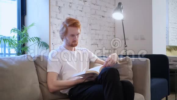创意休闲男子读物坐沙发视频的预览图