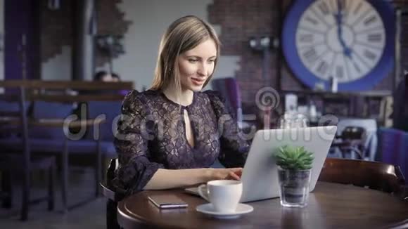 一个白天坐在一家孤独的餐馆里的女人看着笔记本电脑上的约会网站对粉丝的留言做出回应视频的预览图