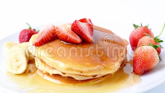 自制煎饼新鲜草莓香蕉片和蜂蜜片放在白色盘子里健康早餐视频的预览图