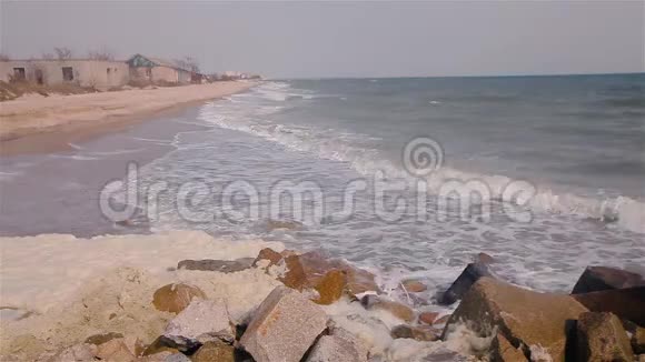 海浪在海边的岩石上破碎海浪沿着海岸翻滚暴风雨前的天气视频的预览图