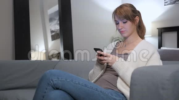 女性在卧室使用智能手机的成功反应视频的预览图