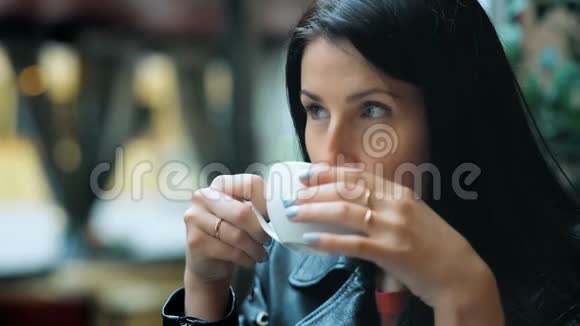 一位美丽的年轻女子在咖啡馆的窗口边喝着热咖啡做梦视频的预览图