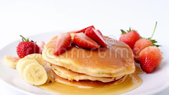 自制煎饼新鲜草莓香蕉片和蜂蜜片放在白色盘子里健康早餐视频的预览图