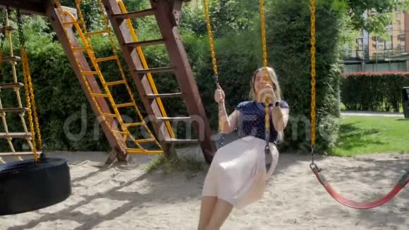 公园操场上快乐微笑的女孩骑着秋千的慢镜头视频的预览图