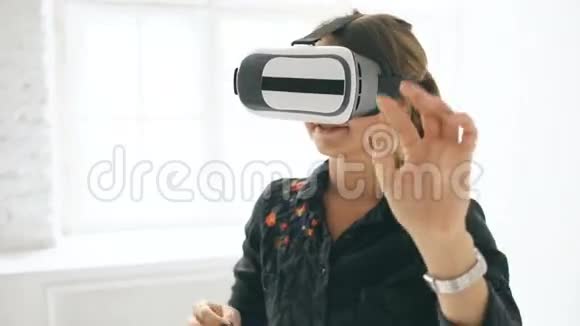 在室内的白色房间里VR耳机里的女人抬起头试图触摸虚拟现实中的物体视频的预览图