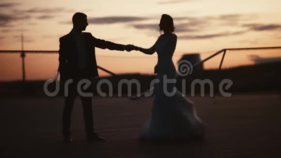新婚夫妇在夕阳下拥抱的剪影视频的预览图