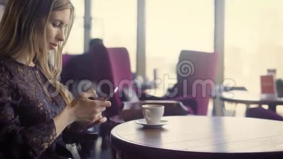一个迷人的女人在咖啡馆里喝一杯咖啡她在智能手机上与社交网络中的朋友交流视频的预览图