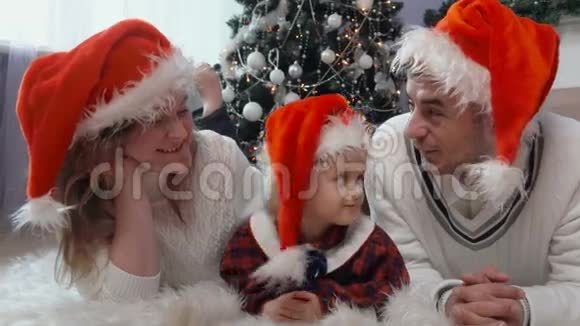 戴着圣诞老人帽子幸福家庭地毯上视频的预览图