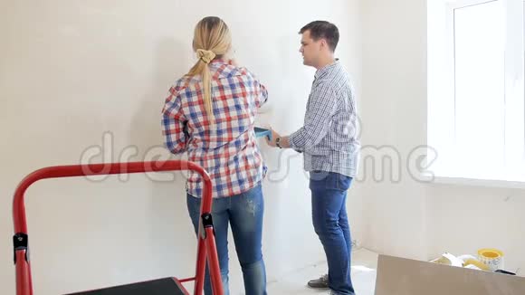 有妻子的年轻人在新房粉刷墙壁的慢镜头视频的预览图