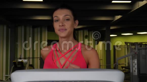 在运动健身房的跑步机上跑步的迷人的混血女人视频的预览图