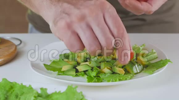 厨房里的一个男人正在准备一份牛油果和樱桃番茄沙拉视频的预览图