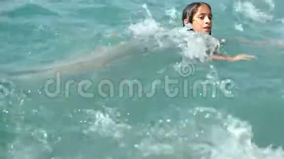 一个十几岁的女孩在海滩上洒成海浪她抓住了波浪很高兴4k慢动作视频的预览图