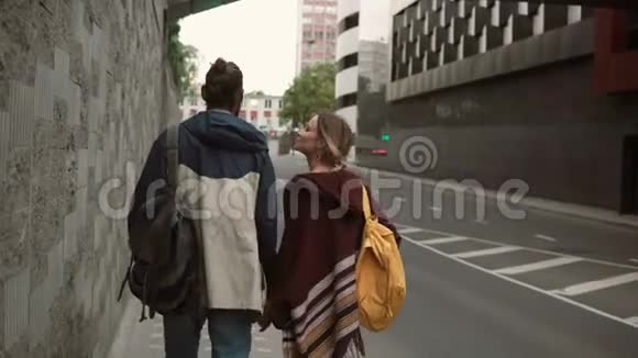年轻漂亮的夫妇带着背包在晚上靠近马路的地方散步男人和女人在一起视频的预览图