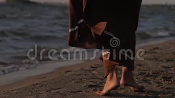 女人在夕阳大海的背景下跳舞裙子贴紧布在风中视频的预览图