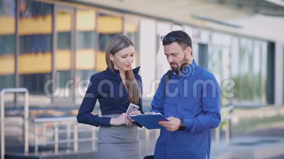 街道商业中心休息期间的办公室经理一个女人看着剪贴板上的信息一个男人视频的预览图