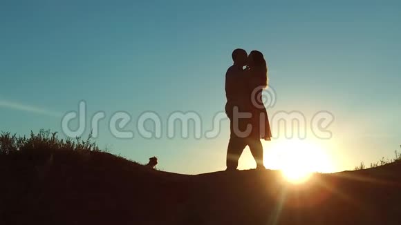 情侣在夕阳下剪影亲吻拥抱慢动作录像年轻夫妇在日落时接吻每个男人和女孩见面视频的预览图