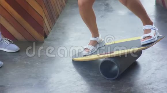 女性腿部特写夏天阳光明媚的一天平衡板上的女人摇床托辊板椭圆形木制甲板视频的预览图