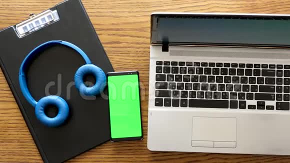 办公桌上笔记本电脑旁边有绿色屏幕的智能手机视频的预览图