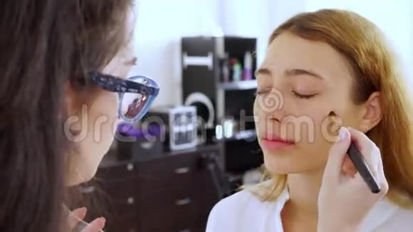 化妆师给模特的女孩化妆下的女人人靠近镜头视频的预览图