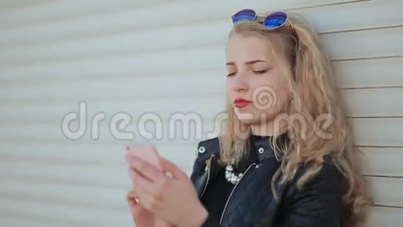 时尚年轻漂亮的女孩手里拿着智能手机女孩在看手机屏幕反对视频的预览图