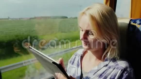 一个年轻的女人乘公共汽车旅行享受平板电脑窗外是一个风景如画的地区公共汽车很快就开走了视频的预览图