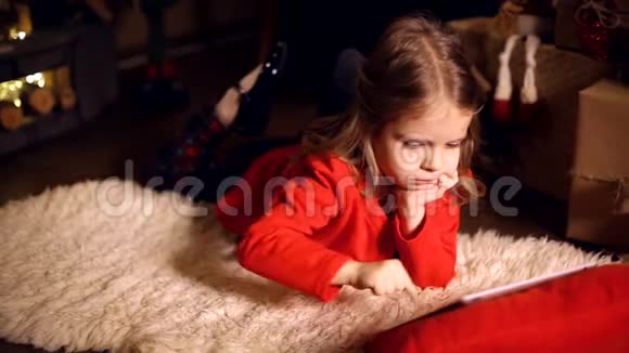 小女孩躺在地毯上拿着礼物在桌上视频的预览图