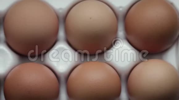 在白色托盘中产卵的十个橙壳蛋的俯视图视频的预览图