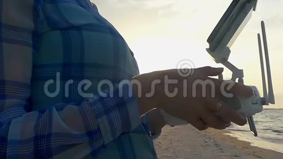 女性手在沙质海岸上控制着一架无人机视频的预览图
