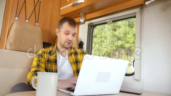一个人用他的笔记本电脑坐在汽车旅馆的桌子旁视频的预览图