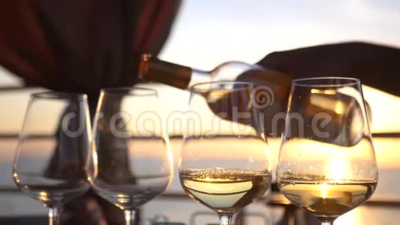 把美味的白葡萄酒倒入玻璃杯中杯中有夕阳和大海的倒影高清1920x1080慢动作视频的预览图